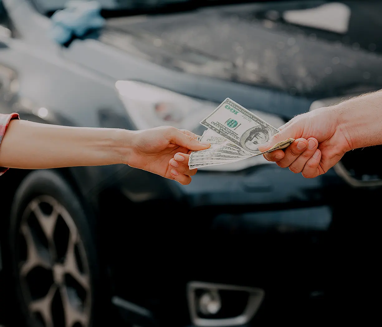 Hands exchanging cash in front of a car, quick cash for cars in Dallas