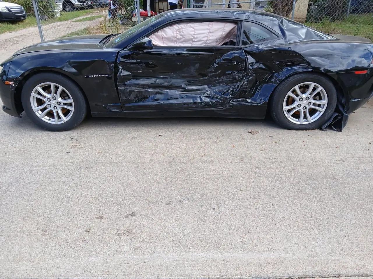 Black Chevrolet Camaro with crushed driver-side doors after an accident