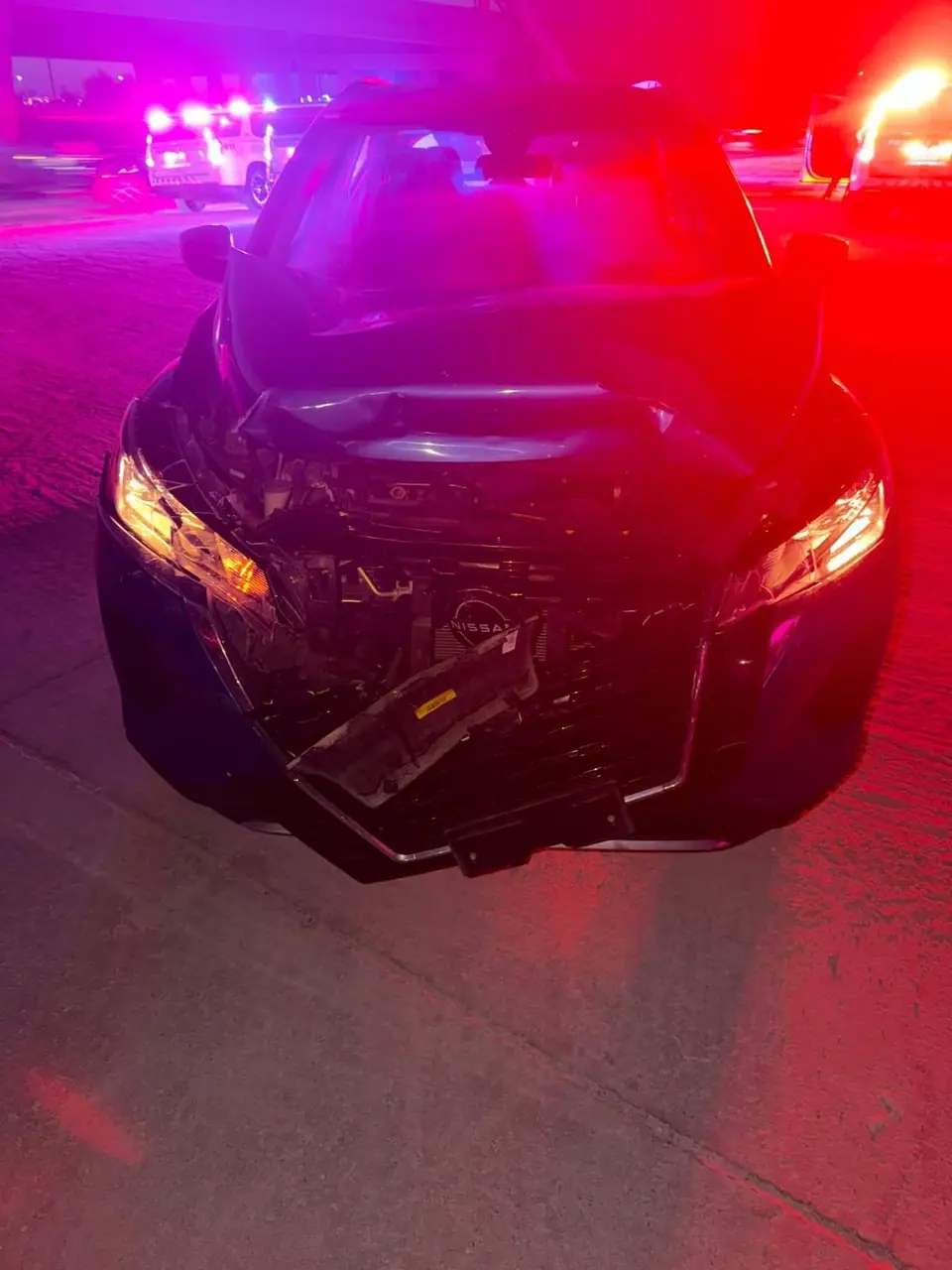 Car with severe front-end accident damage at night