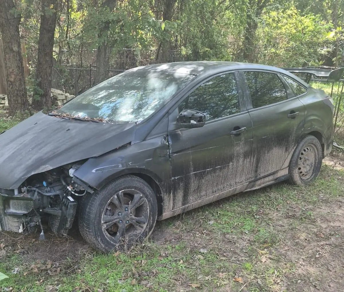 Dark sedan with front-end collision damage, a damaged car we buy