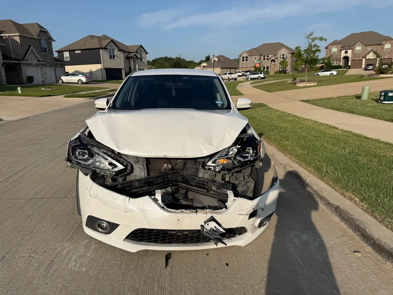 White Nissan sedan with a smashed front end, junk car removal