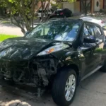 Black Nissan Juke with heavy front-end damage, damaged car buying