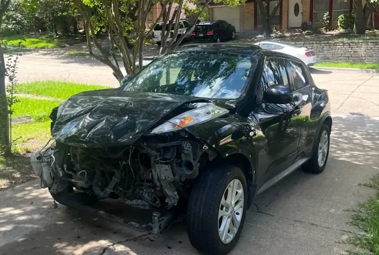 Black Nissan Juke with heavy front-end damage, damaged car buying