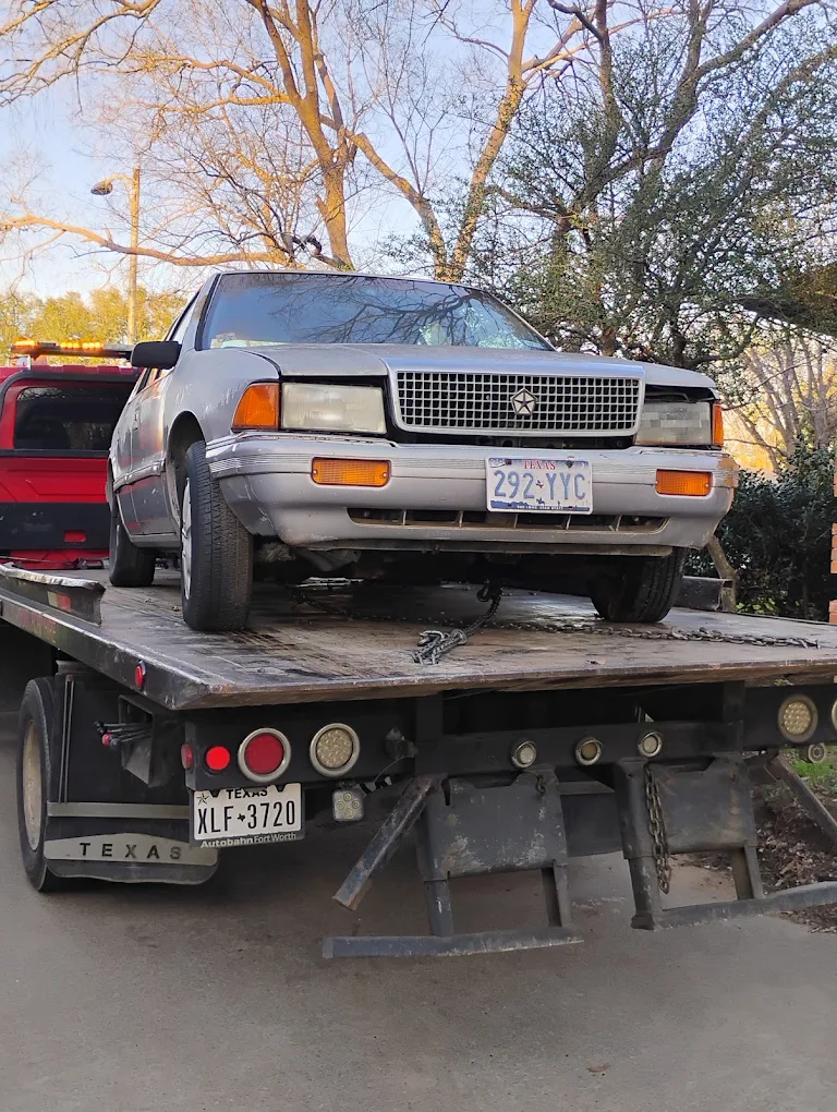 Old silver Chrysler sedan on a flatbed tow truck for free towing