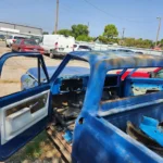 Stripped blue pickup truck in a salvage yard, non-running car buying