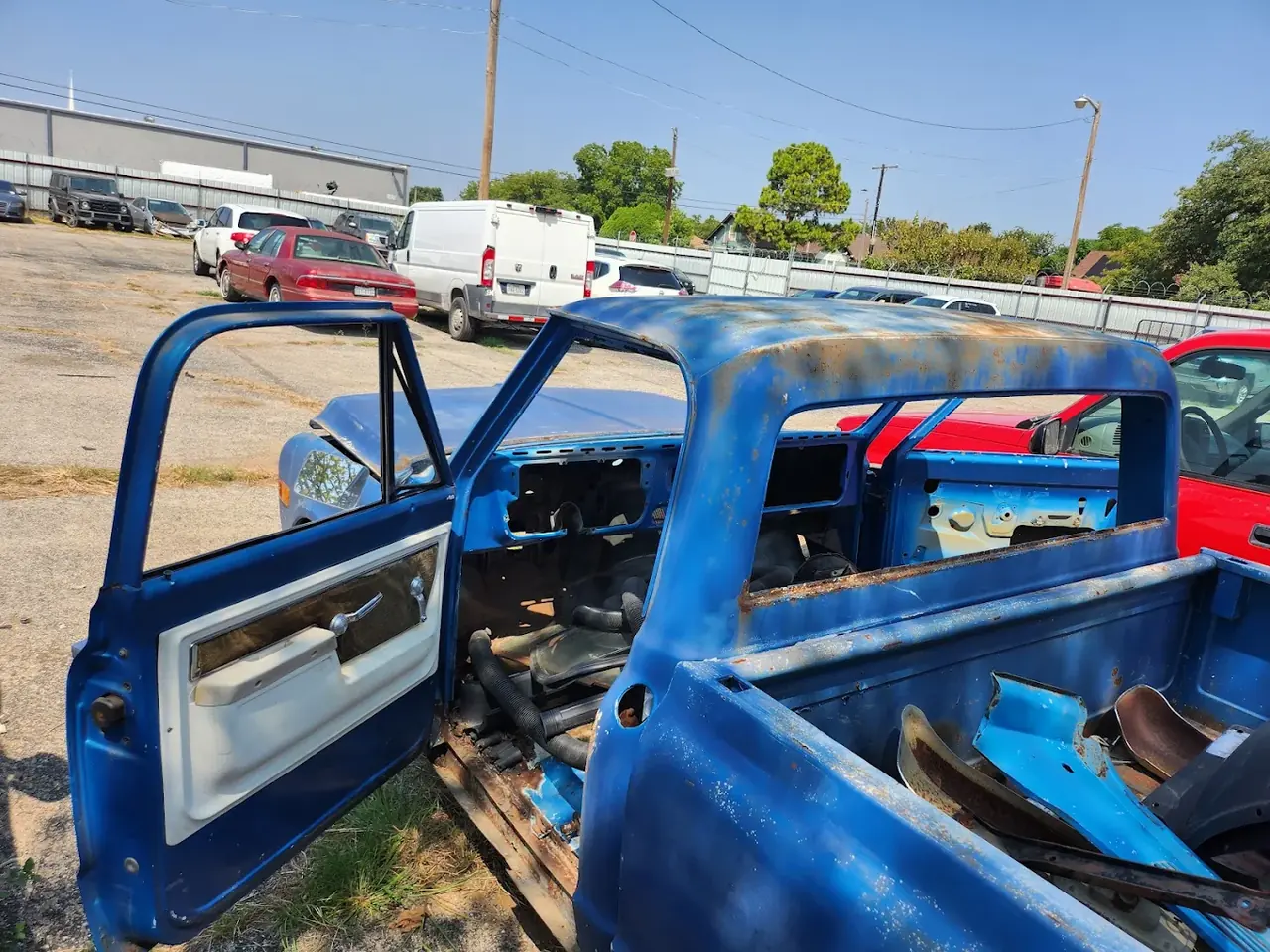 Stripped blue pickup truck in a salvage yard, non-running car buying