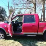 Red Ford F-150 pickup with the door open, unwanted vehicle removal