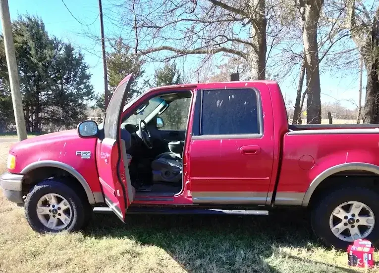 Red Ford F-150 pickup with the door open, unwanted vehicle removal