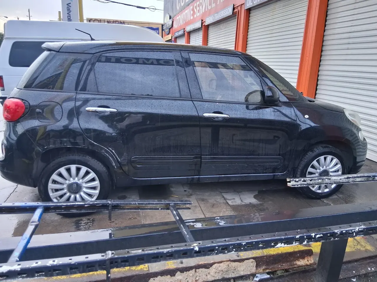 Black hatchback on a tow truck bed for junk car removal