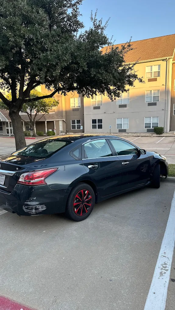 Dark blue Nissan sedan parked at an apartment complex before junk car pickup